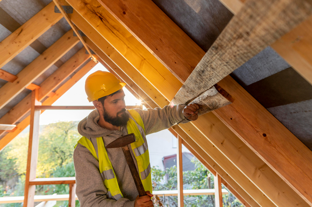 un artisan qi travaille sur une charpente en bois, charpente bois renovation