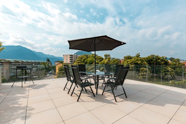 une table avec des chaises et un parasols noirs sur un toit terrasse, toiture terrasse étanchéité