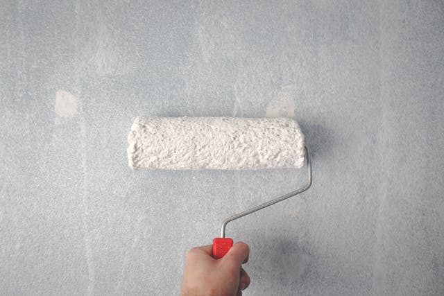 une main qui tient un rouleau pour peindre un mur, peintre toulouse