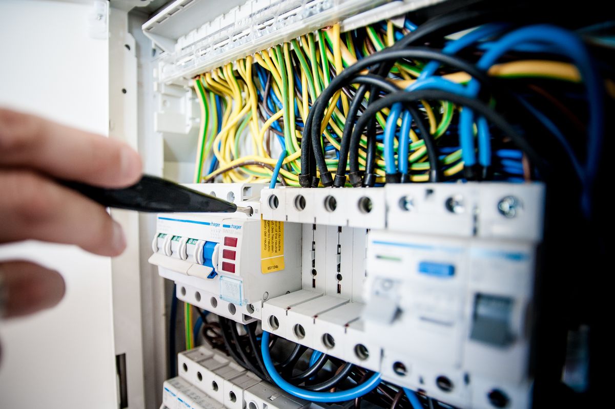 Électricien travaillant sur un tableau électrique avec des fils colorés